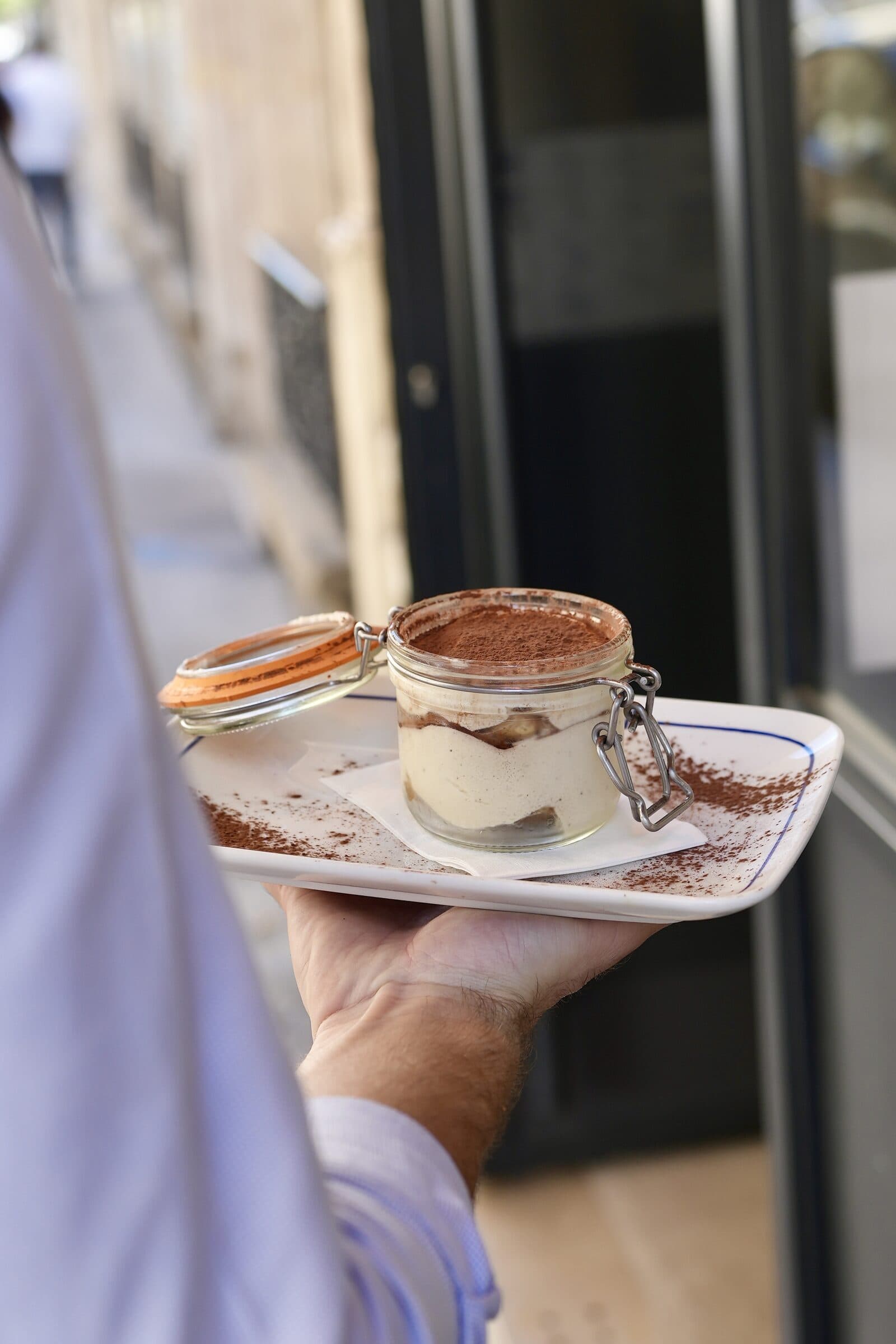 Tiramisu maison en bocal Weck saupoudré de cacao, servi sur assiette Le Comptoir Foch devant l'entrée du restaurant